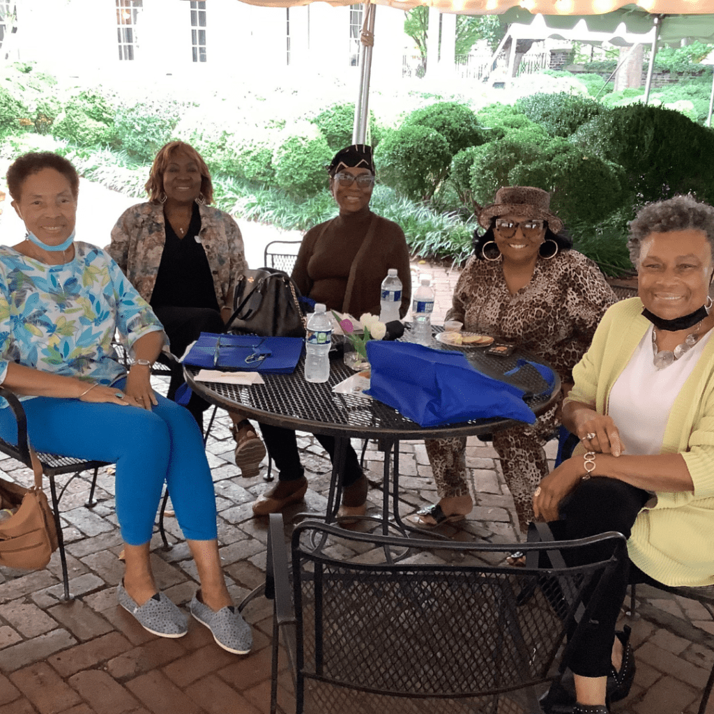Group of senior ladies sitting at an outdoor patio table with Leigh Battle at a recent Medicare event