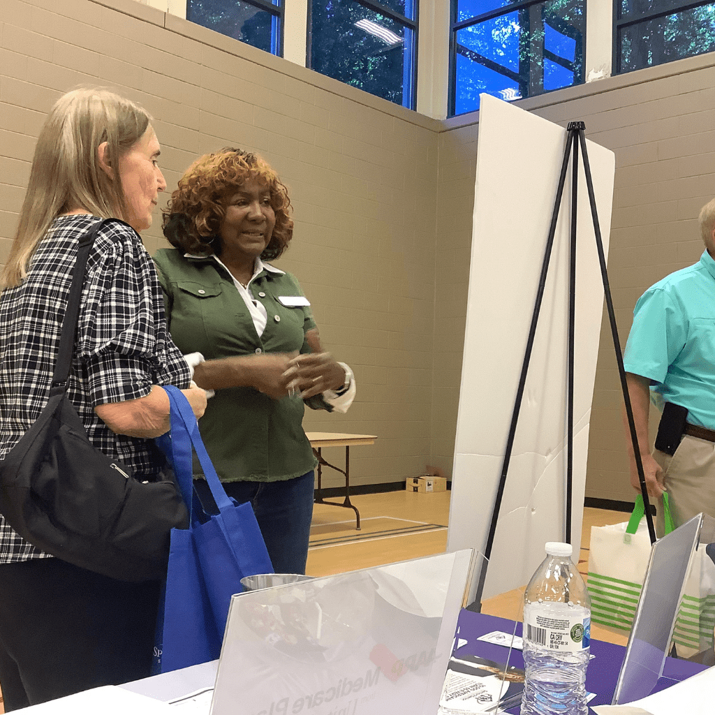 Leigh speaking with senior citizen about Medicare at educational event