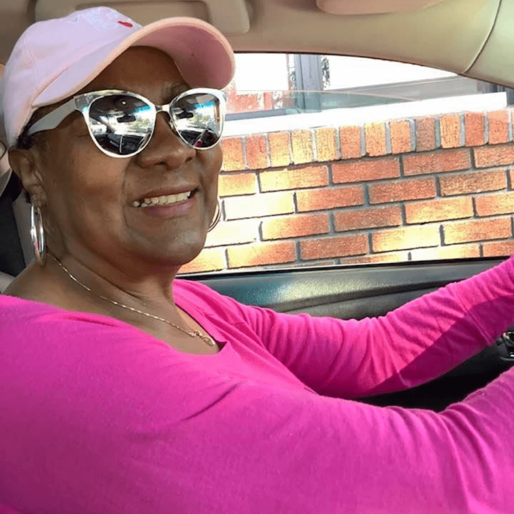 Leigh Battle wearing a pink shirt and hat to recognize Breast Cancer Awareness Month
