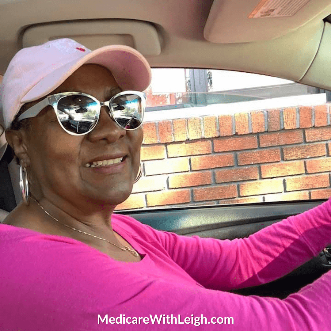 Photo of Leigh Battle smiling, wearing a bright pink shirt and pink hat on her way to a preventive health appointment.