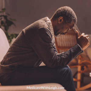 Photo of a senior African American man with his head on his hands while sitting on a sofa, in recognition of Mental Health Awareness Month.