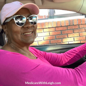 Photo of Leigh Battle wearing a bright pink shirt and a light pink hat in honor of Breast Cancer Awareness Month.